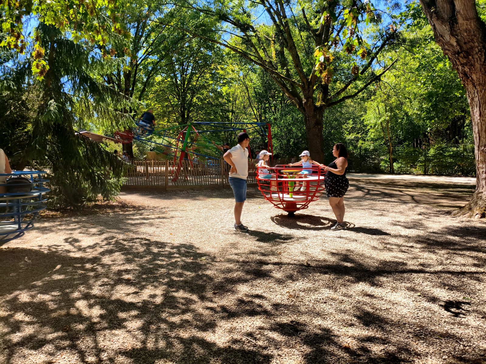 Enfants sur le tourniquet rouge de l'aire de jeux du parc de l'Auxois